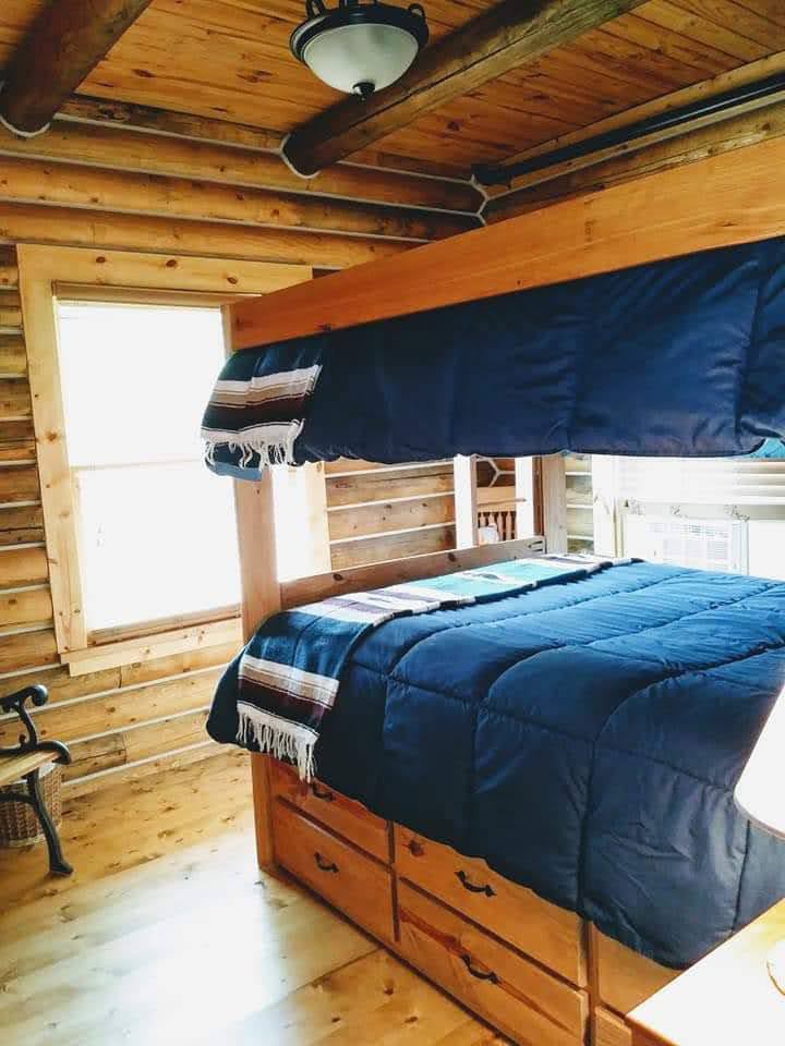 triangle-ranch-cabin-under-the-hill-2 Wooden bedframe in a rustic cabin room.