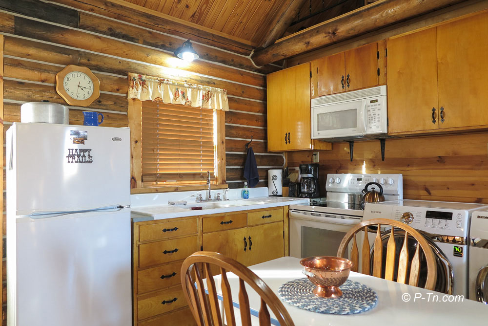 triangle-ranch-cabin-under-the-hill-5 Rustic kitchen with appliances and wood cabinets.