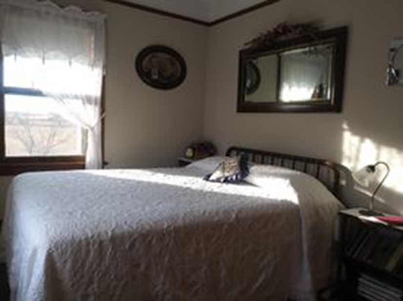 triangle-ranch-esthers-room-3 Bedroom with white bedding, natural light, and wood headboard.